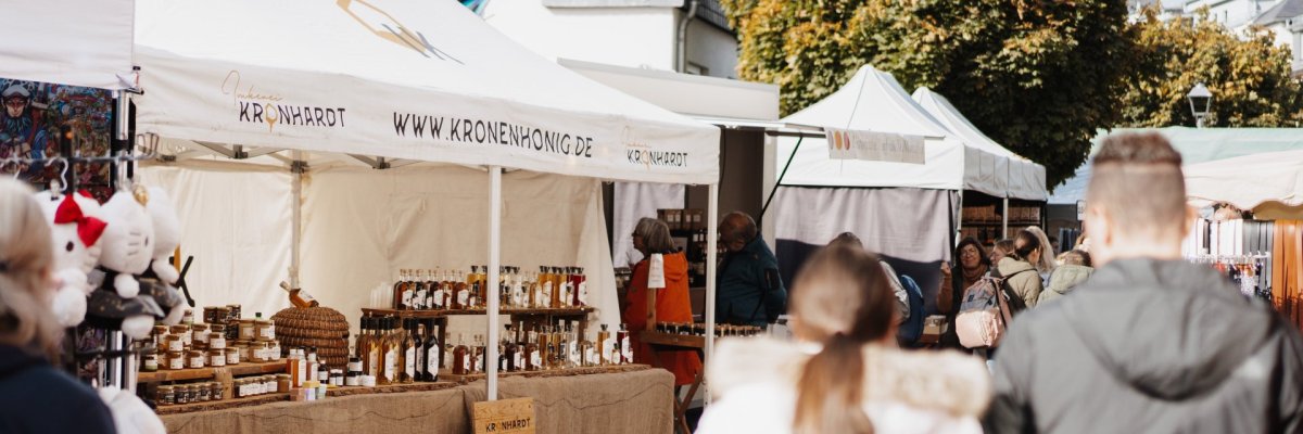 Krammarktstraße zum Lukasmarkt, in der sich viele Verkaufsstände unterschiedlicher Waren aneinanderreihen. Besucher laufen durch die Straße und stöbern an den Ständen
