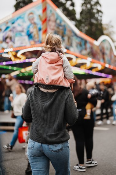 Besuch auf dem Lukasmarkt, Mädchen sitzt auf den Schultern der Mutter